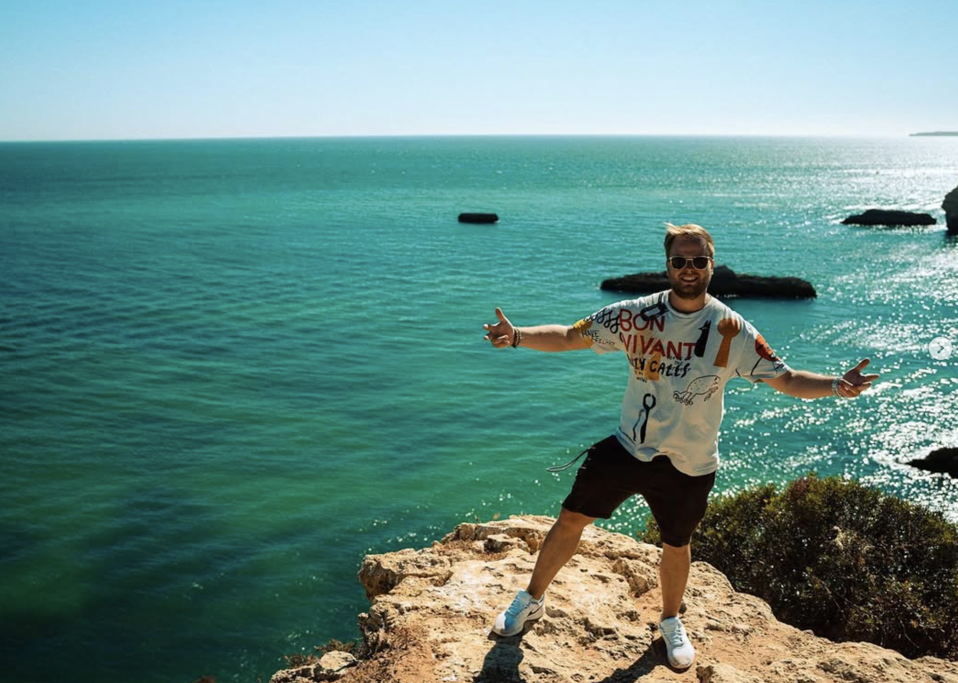 Stefan Aigner im bunten Shirt auf einer Klippe am Meer